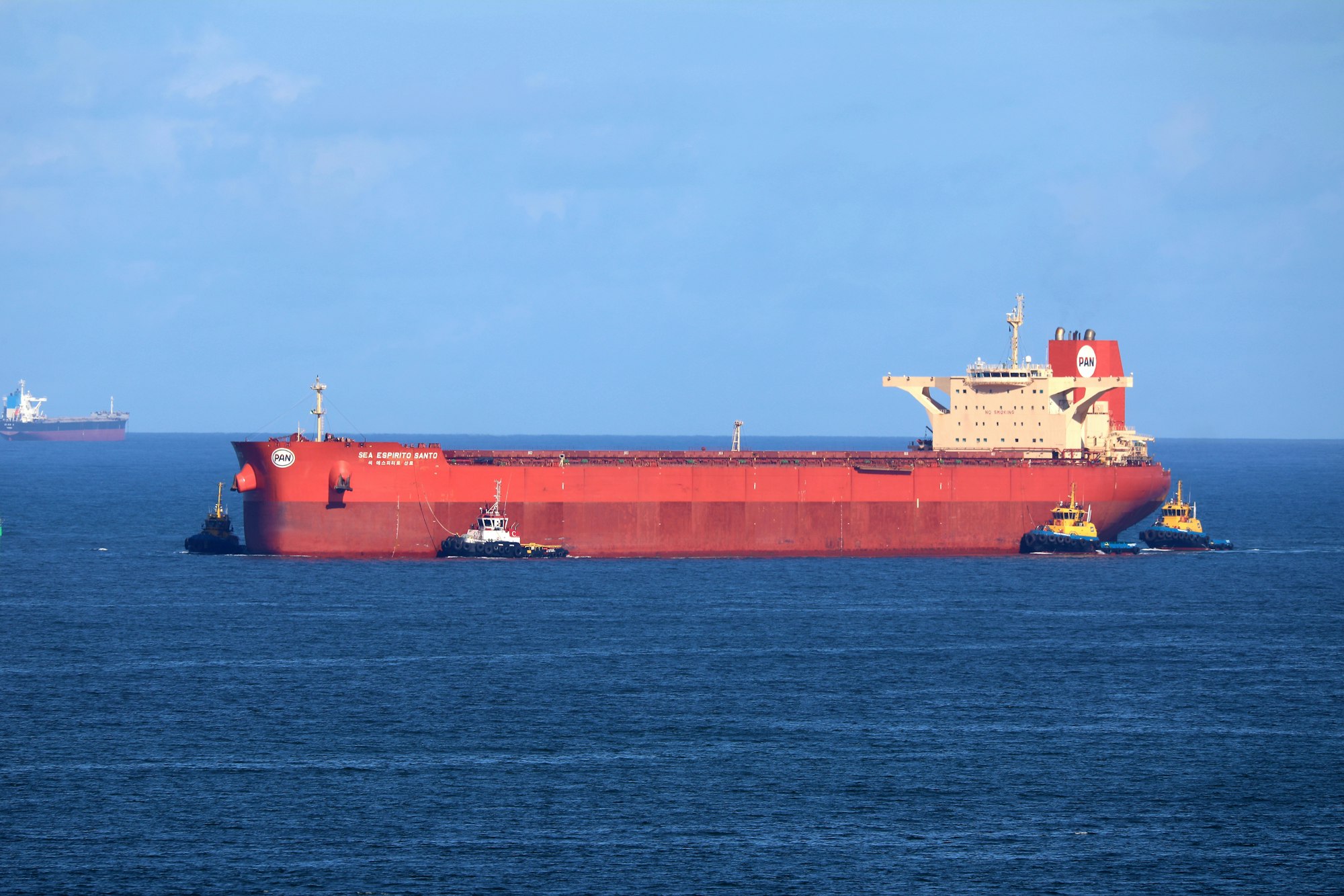 Bulk carrier with tugs alongside at sea